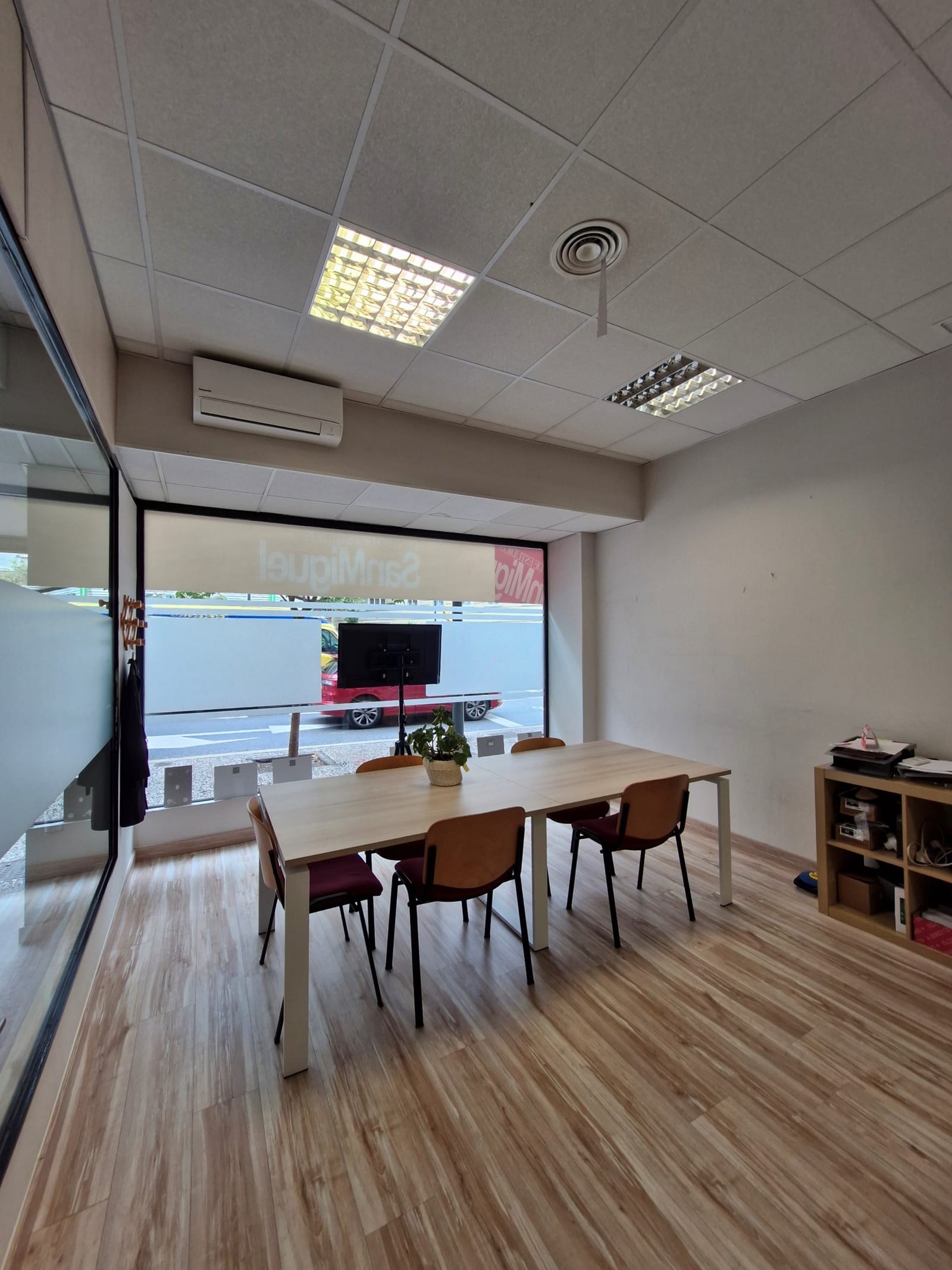 Sala de reuniones y profesores del centro Formación San Miguel en Zaragoza, con mesa formal para seis personas, sillas tapizadas, panel de cristal con vinilo corporativo, climatización y vista al exterior